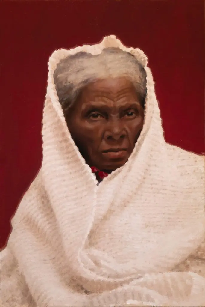 Bust of Harriett Tubman in her older age, in front of a red background, with her head and shoulders draped with a white blanket