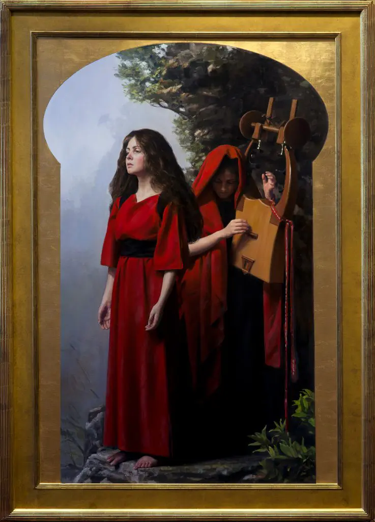 Brunette woman wearing red robe, standing along a rocky overlook, with another woman in red robes playing a string instrument behind her