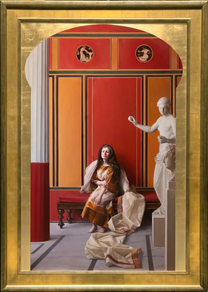 Brunette woman in white and gold robe, sitting on a bench in a museum next to a white statue