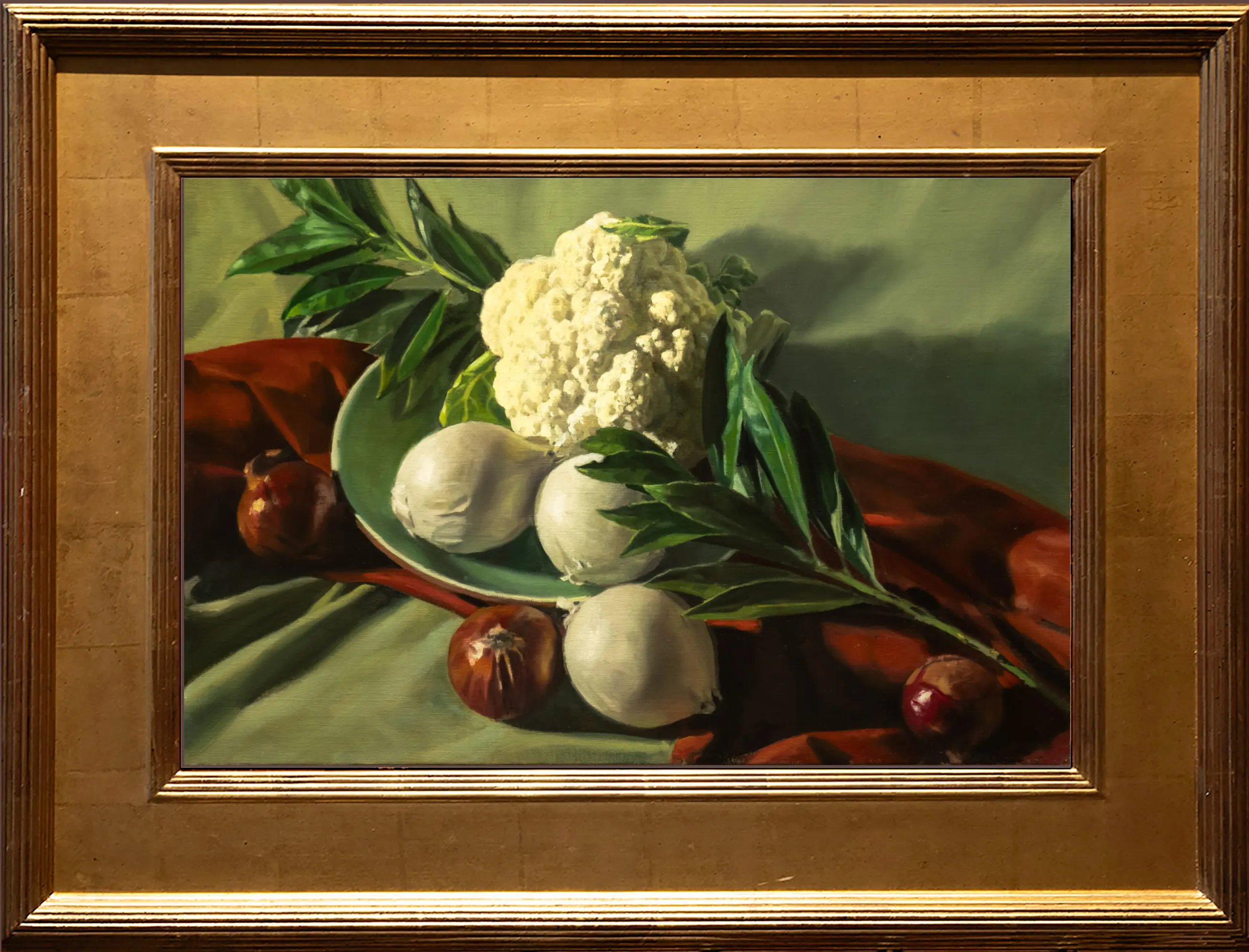 Cauliflower and white onions sitting in a green bowl in front of a green backdrop