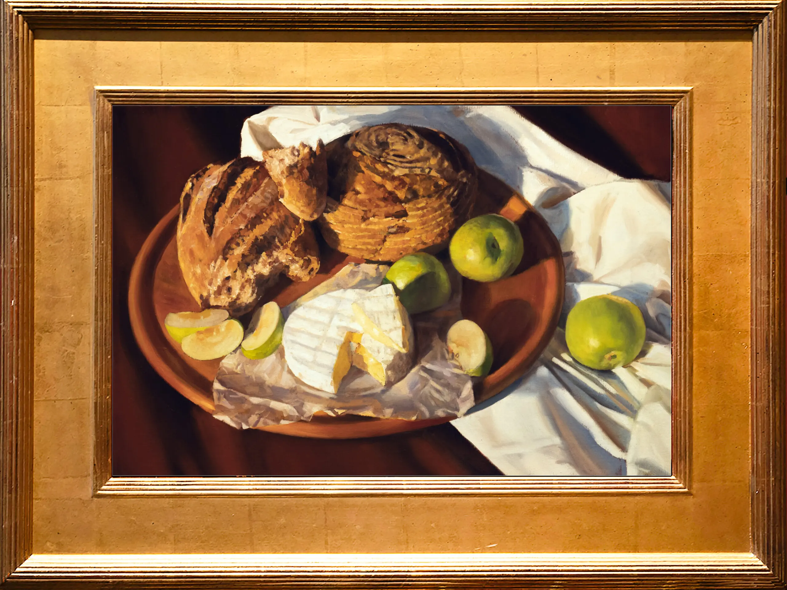 Baked bread sitting on a platter with brie cheese and apples on an orange tinted back drop